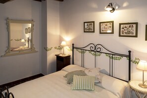 Une chambre à coucher avec un lit, des lampes de chevet, un miroir et des tableaux encadrés accrochés au mur.