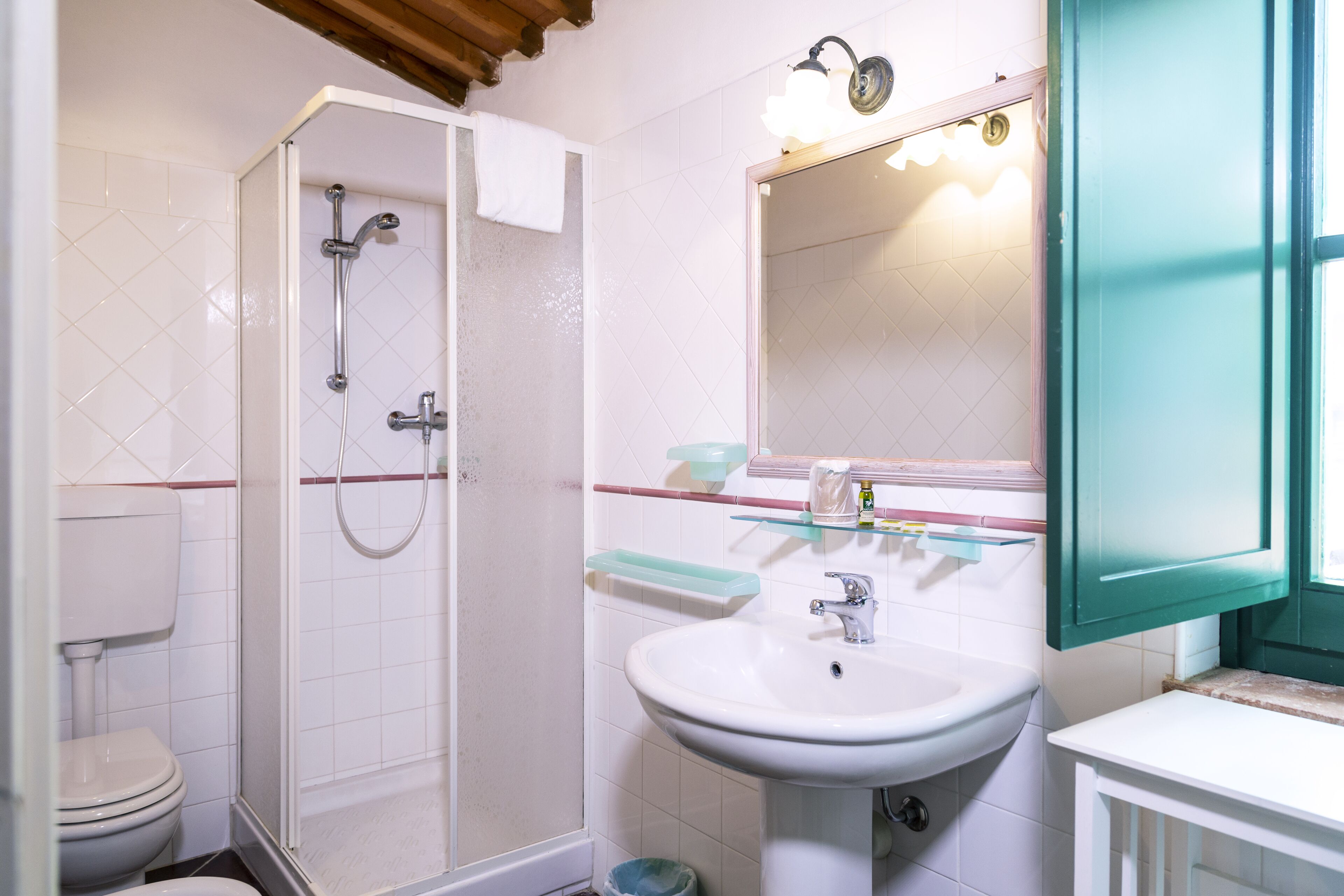 A bathroom with a shower, toilet, sink, and a mirror with lights.