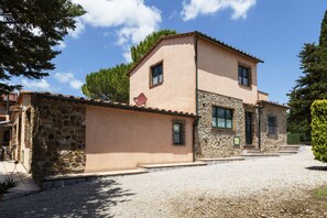 Un bâtiment en pierre de deux étages, doté d’un toit en pente, d’une allée gravillonnée et d’un mur de pierre sur le côté gauche.