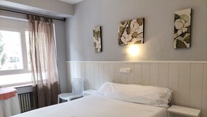 A neatly made bed with a rolled towel, a white chair, and a small bedside table. - Hostal Albero by gaiarooms (Salamanca)