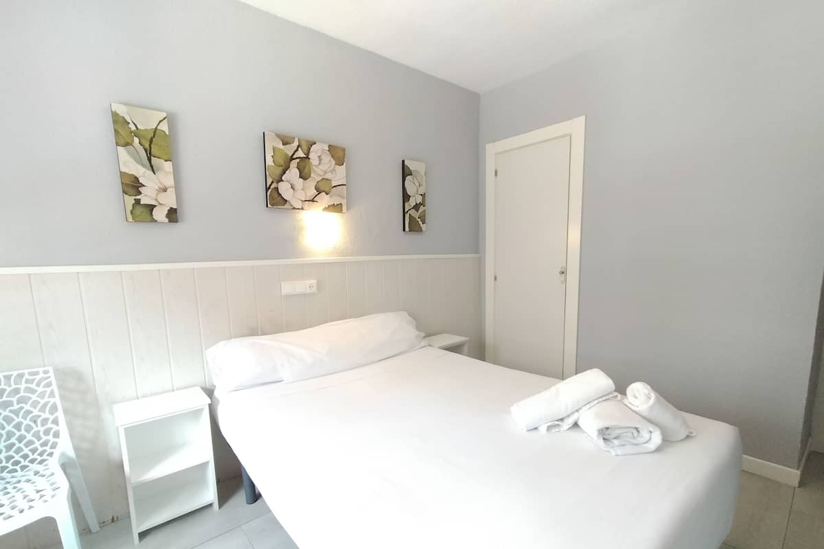 A hotel room with a large bed, a small bedside table, and wall-mounted artwork.
