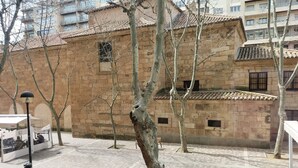 A courtyard with a tiled floor, a brick building with multiple windows, and a few trees. - Hostal Albero by gaiarooms (Salamanca)