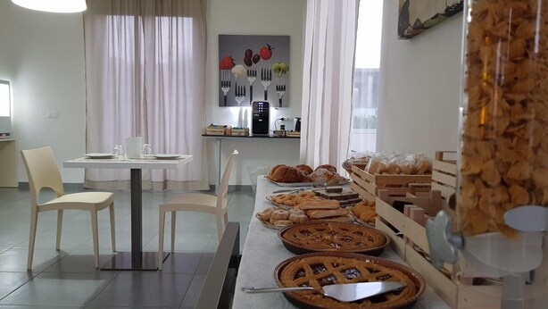 A modern kitchen with a dining area, featuring a long counter with baked goods and a coffee machine. - Dodo House Bed & Breakfast (Nocera Inferiore)
