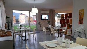 A modern dining area with tables and chairs, a television, and a view of the outside. - Dodo House Bed & Breakfast (Nocera Inferiore)