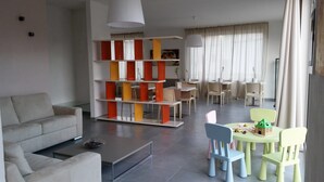 A modern living room with a sofa, coffee table, and colorful chairs. There is a dining area with a table and chairs, and a bookshelf with red and yellow accents. - Dodo House Bed & Breakfast (Nocera Inferiore)