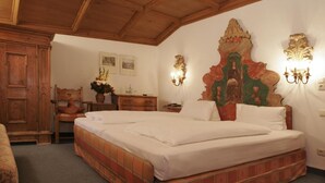 Un dormitorio con una cama grande, cabecera de madera, dos lámparas fijadas a la pared, un armario de madera y un escritorio con silla.