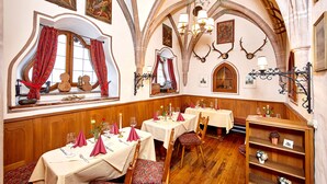 Un comedor con mesas dispuestas para cuatro, sillas de madera y un banco de madera.