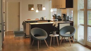 Cozinha moderna com duas cadeiras, uma mesa de jantar e luminárias pendentes.