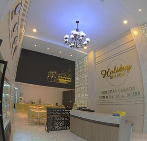 A hotel lobby with a reception desk, seating area, and a wall with 'Holiday Season' signage. - Holiday Season Motel (Yangon)