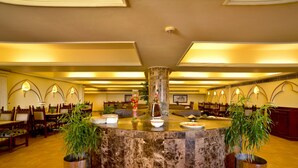 Un hall d’entrée doté d’un comptoir de réception central en marbre, de plusieurs espaces aménagés pour s’asseoir et d’un éclairage décoratif.