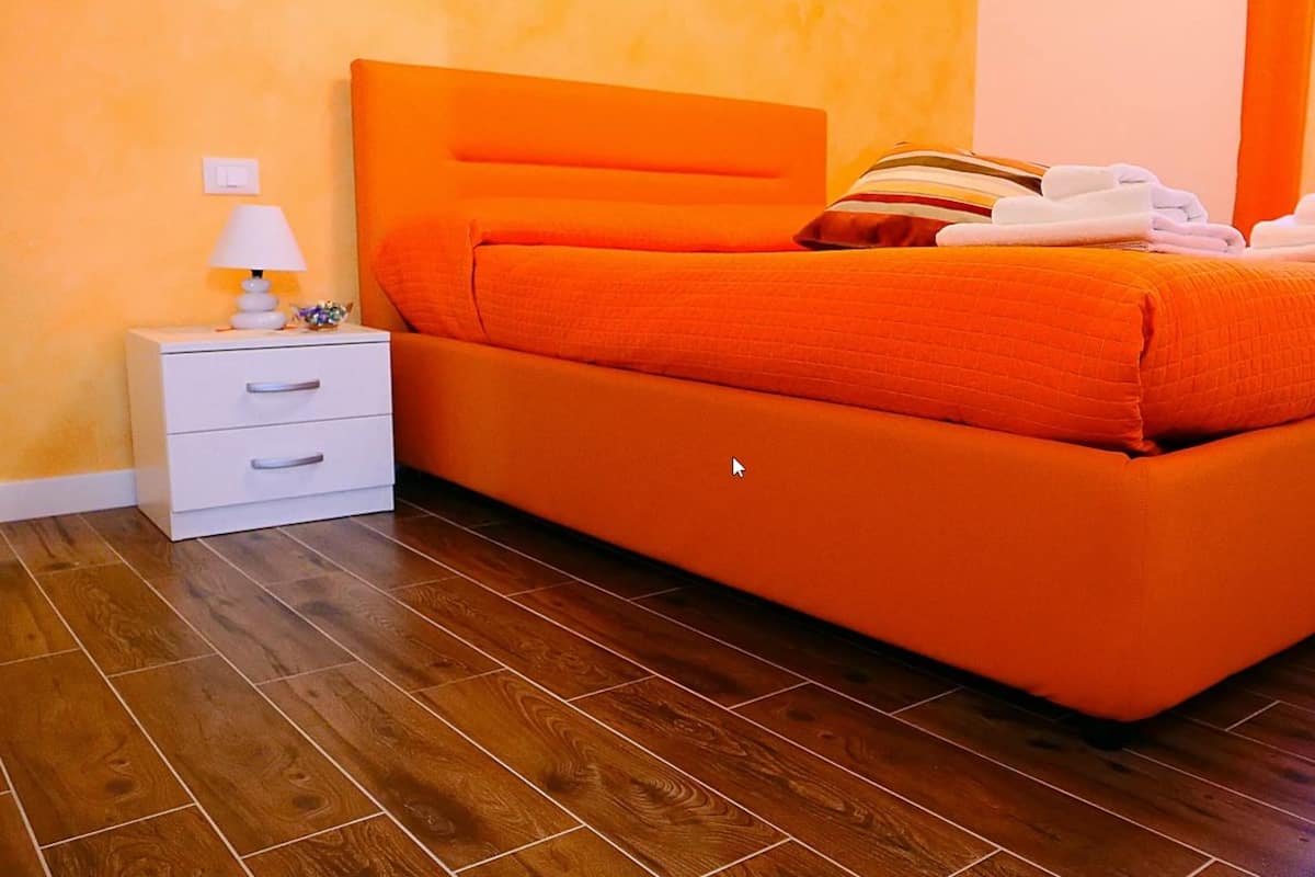 A room with a bed, a nightstand, a lamp, and a drawer unit.