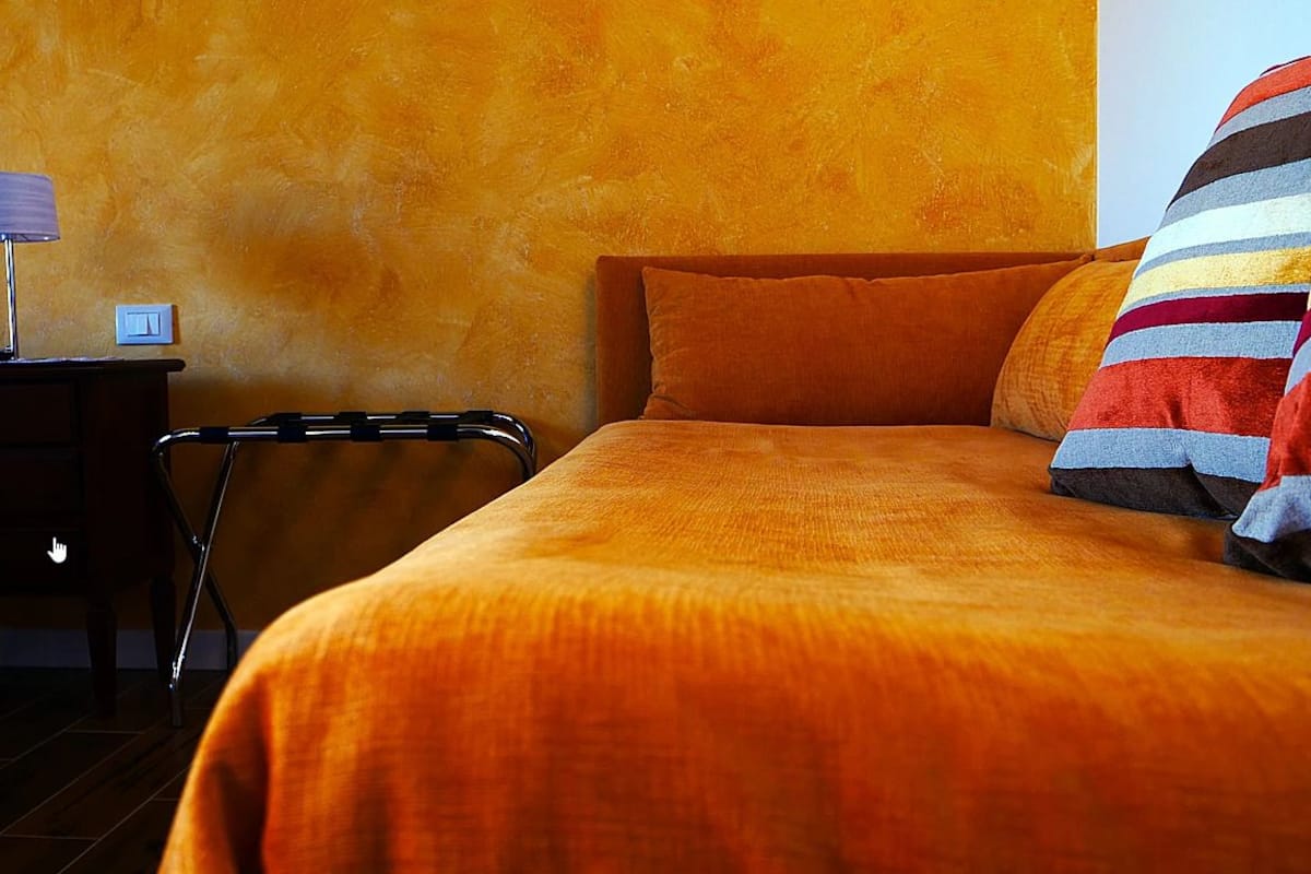 A room with a bed, a nightstand, a lamp, and a wheelchair.