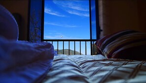 A bed with a view of a clear blue sky through a window with vertical bars. - Antico Borgo San Francesco (Longi)