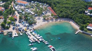 An aerial view of a coastal area with a marina, beach, and residential buildings.