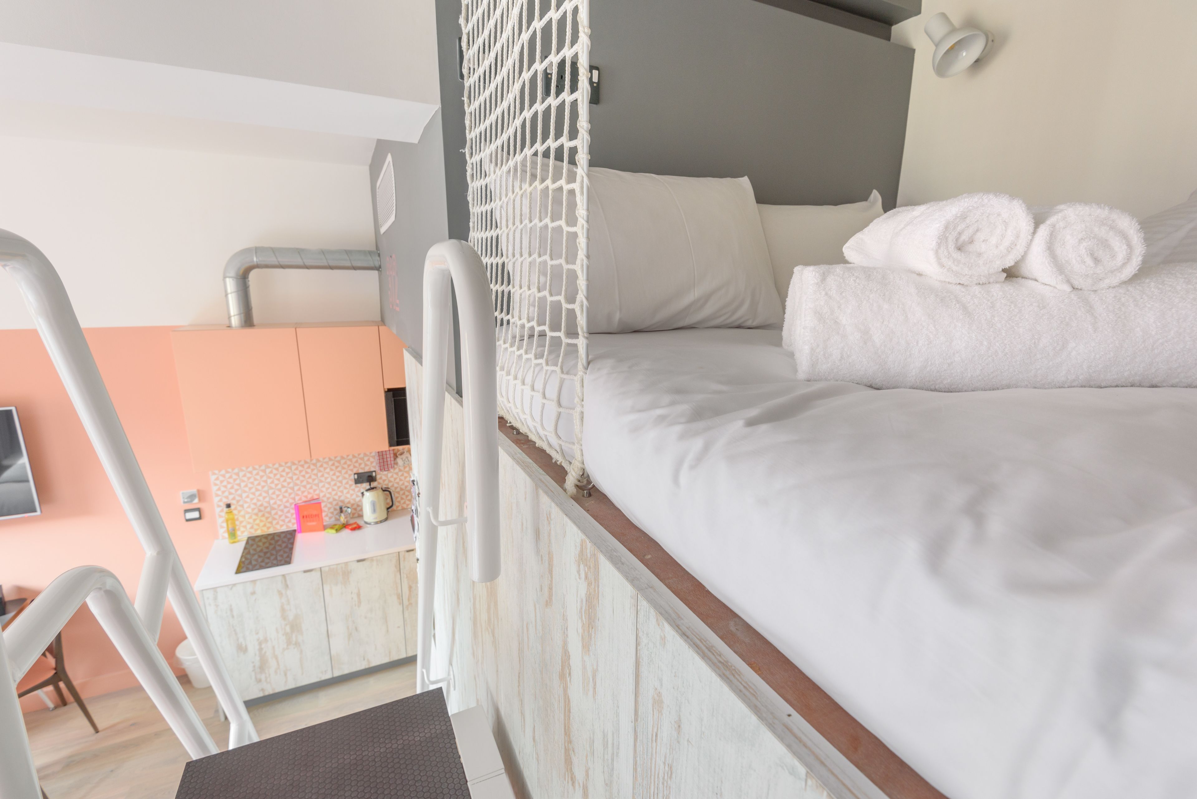 Une chambre avec un lit superposé, un bureau avec une chaise et un coin cuisine.