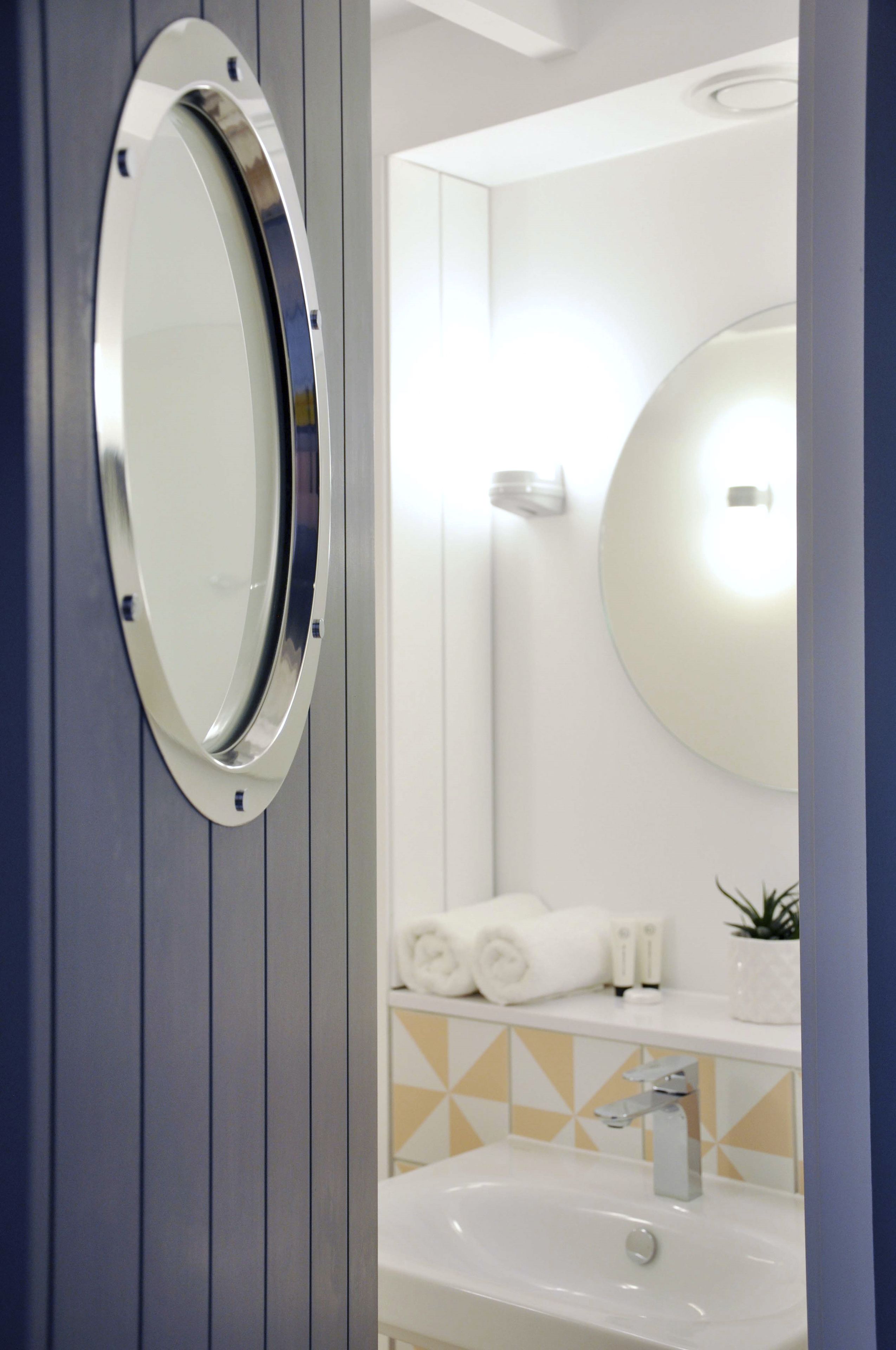 Un baño con un espejo redondo, un lavabo y un perchero para toallas.