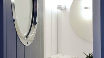 Un baño con un espejo redondo, un lavabo y un perchero para toallas.