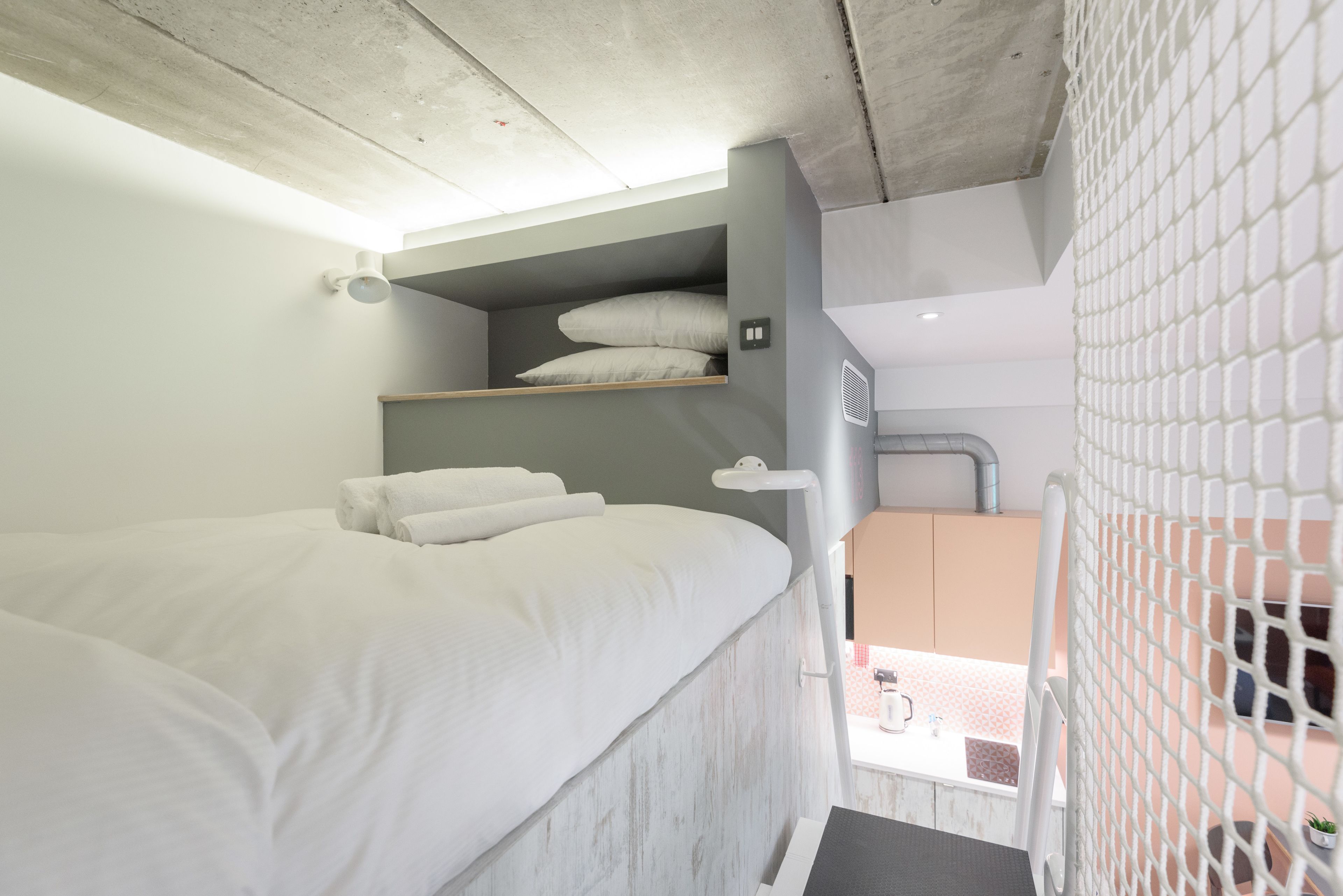 A modern hotel room with a bed, a small seating area, and a view of the outside.