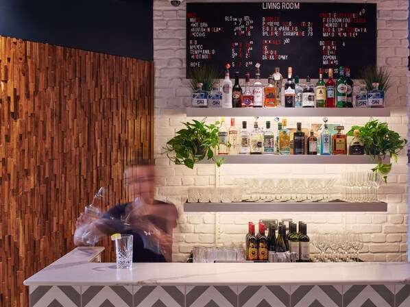 A bar area with a wooden wall, a menu board, and various bottles and glasses.