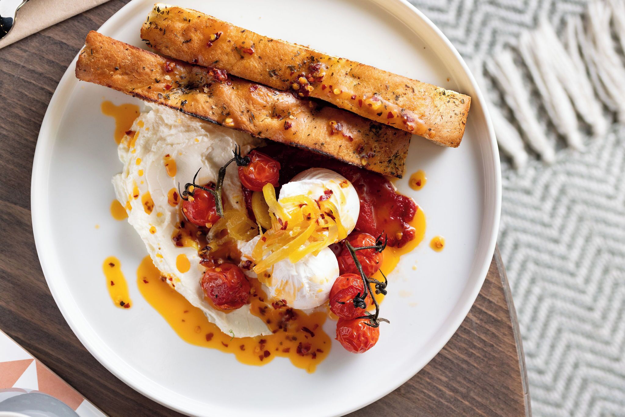 A plate with a poached egg, cherry tomatoes, and a drizzle of sauce.