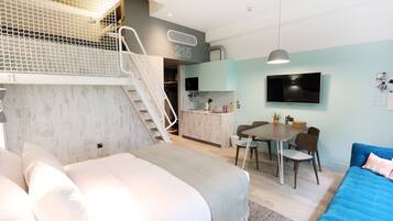 Un apartamento moderno con un entrepiso con cama, comedor y cocina.