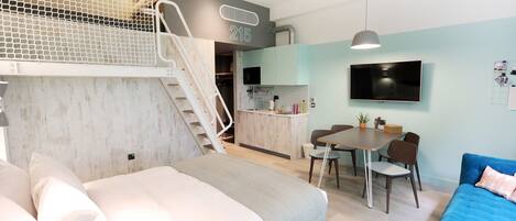 Un apartamento moderno con un entrepiso con cama, comedor y cocina.