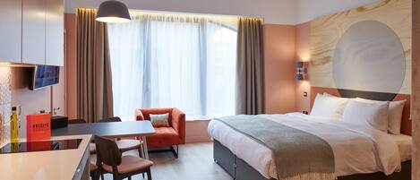A modern hotel room with a bed, a desk, a chair, and a television.