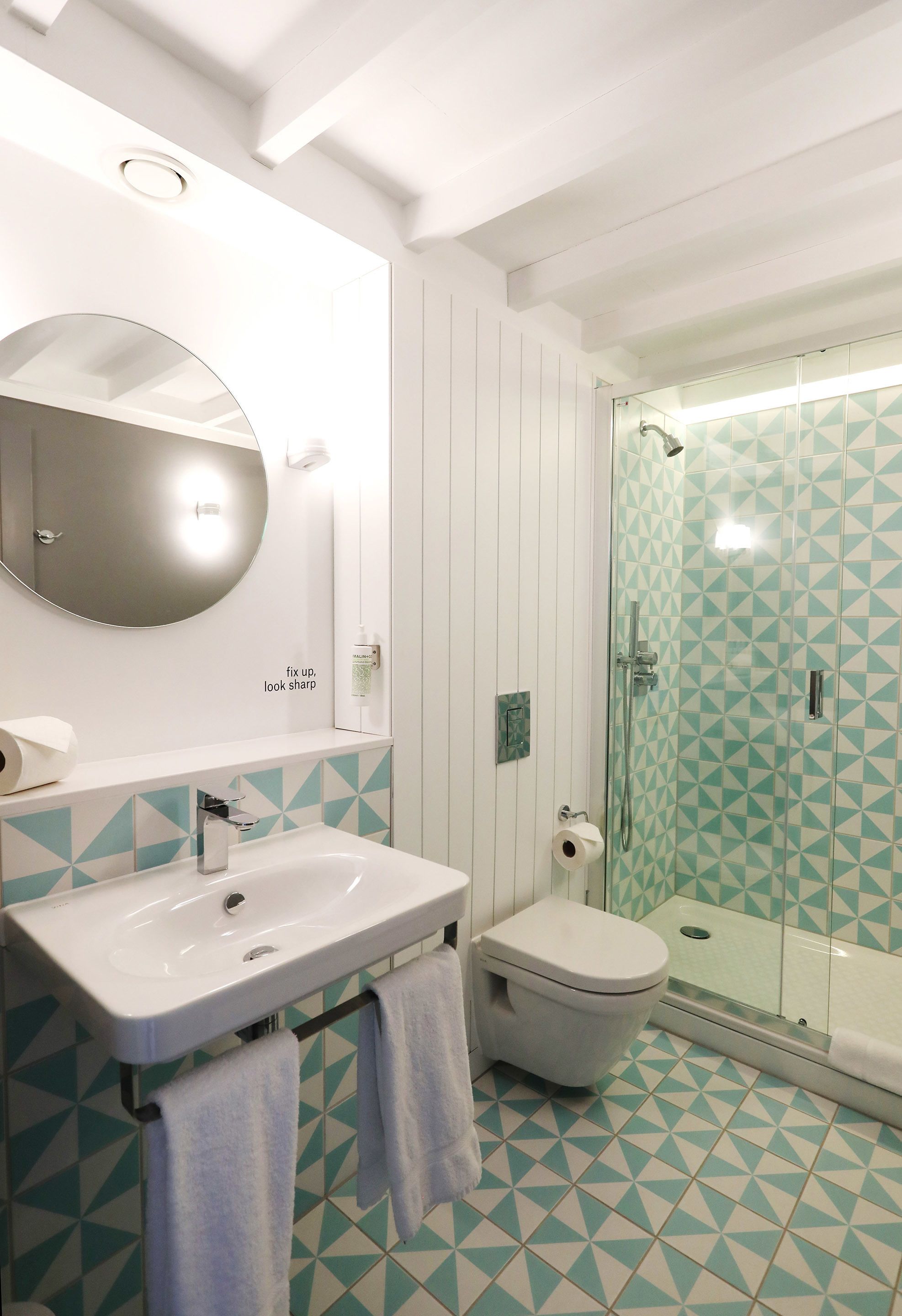 Een badkamer met een witte wastafel, een toilet en een douche met glazen wanden.
