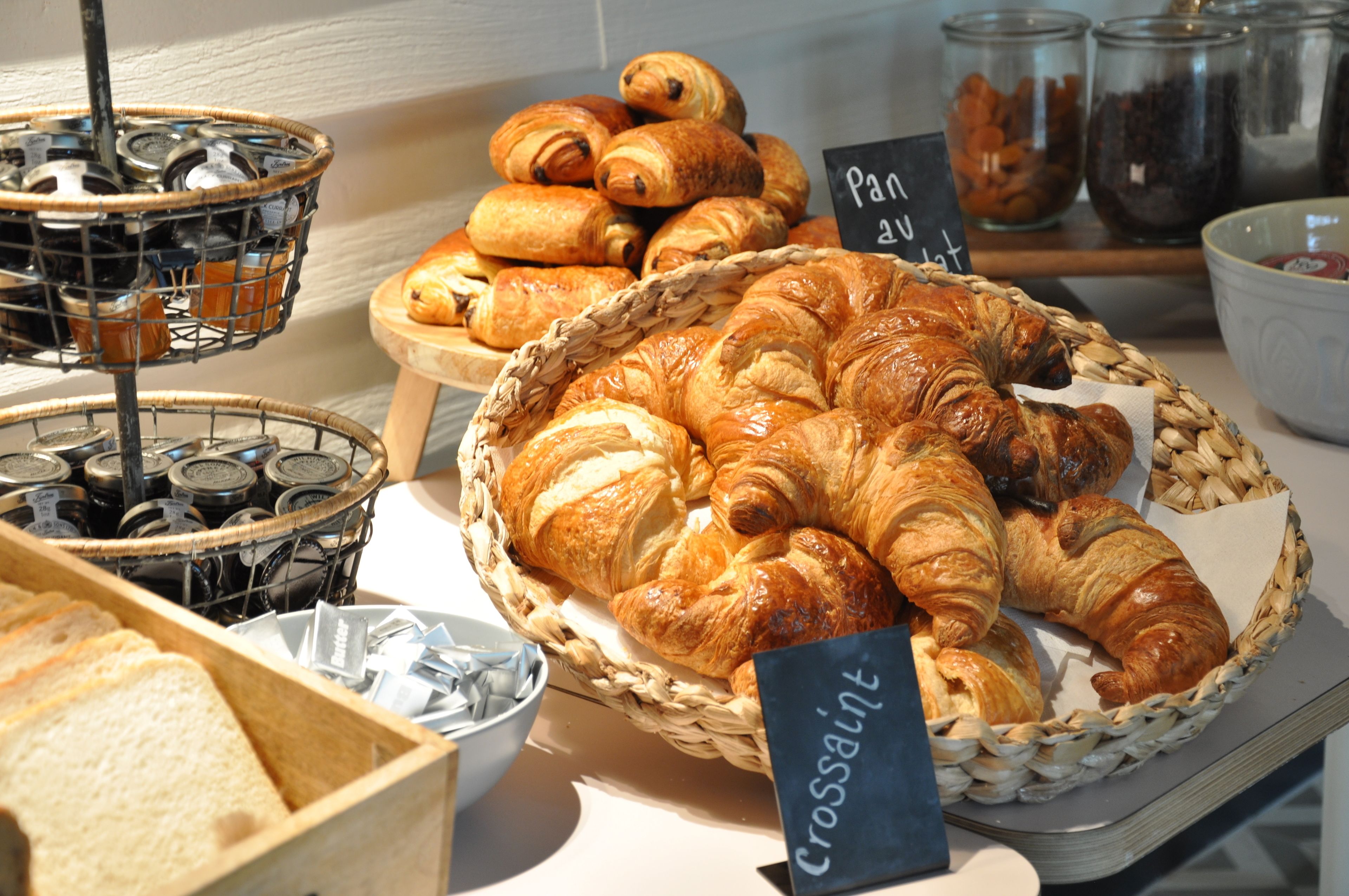 A display of croissants and bread in a bakery setting.
