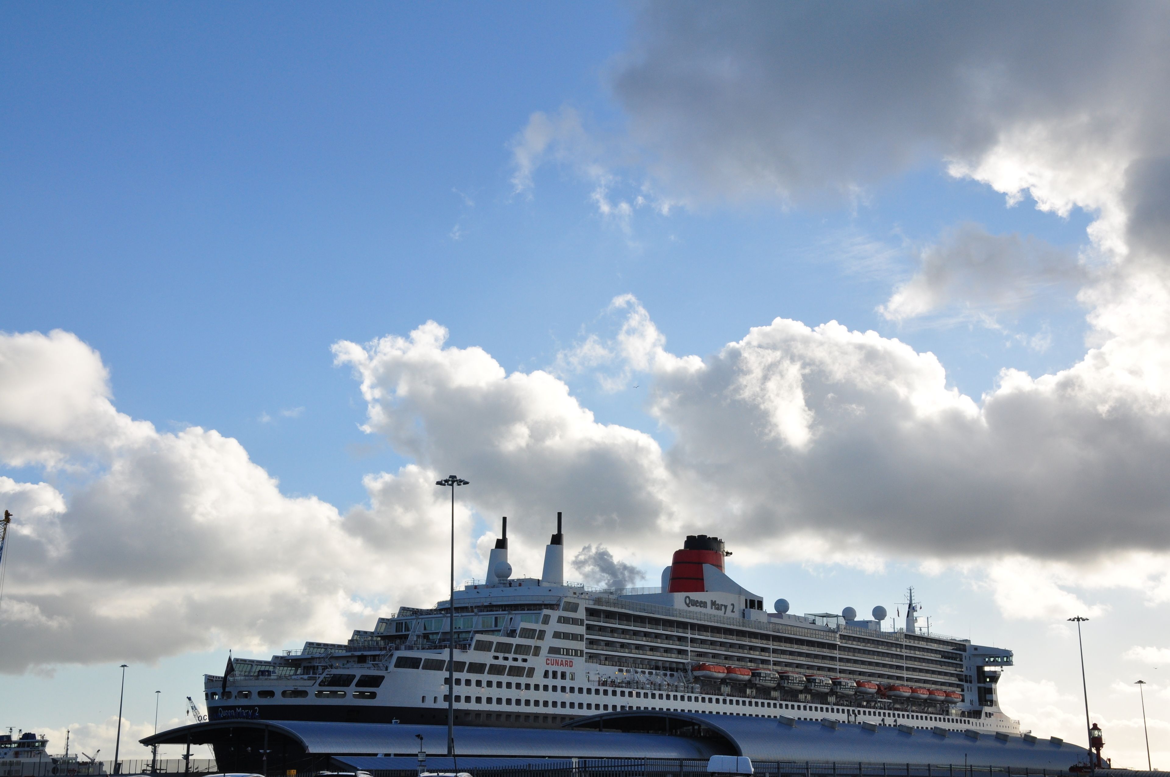 A large cruise ship named 'Queen Mary 2' docked at a port.
