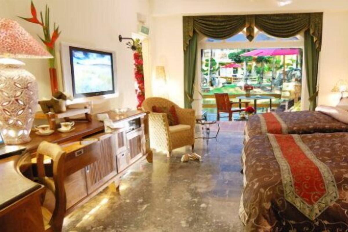 Una habitació d'hotel amb un llit, un escriptori amb un ordinador, una cadira i vista a l'exterior.