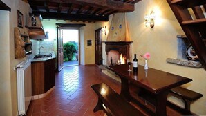 Um interior rústico com uma mesa de madeira, bancos e lareira.
