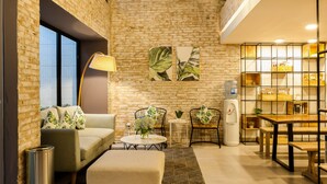 A modern interior with a brick wall, a sofa, a coffee table, and a dining area with a table and chairs. - La Regatta Boutique Residences (Ho Chi Minh City)
