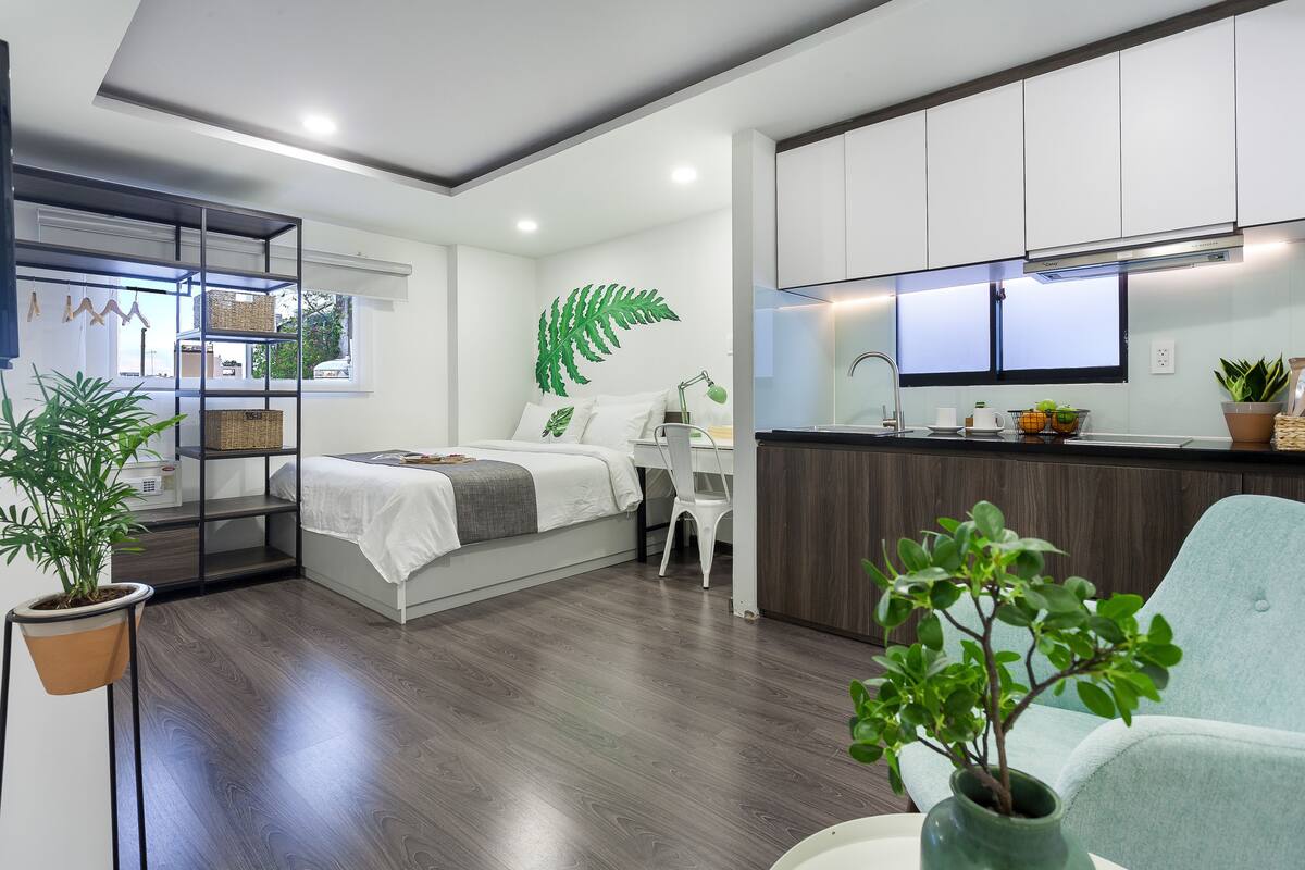 Quarto moderno com cama, mesa de cabeceira e uma grande janela.
