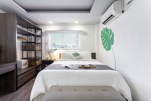 Een moderne slaapkamer met een bed, een kledingkast, een raam met uitzicht op de stad en een grote groene bladdecoratie aan de muur.