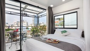 A modern hotel room with a large balcony, a bed with white linens, and a tray of fruit. - La Regatta Boutique Residences (Ho Chi Minh City)