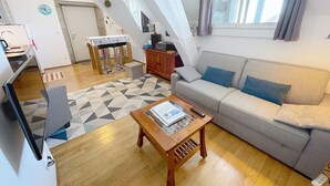 Un salon comprenant un canapé, une table basse, une table à manger avec des chaises et un coin cuisine.