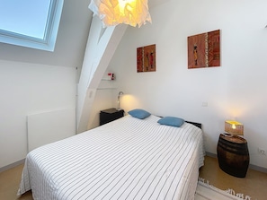 Een slaapkamer met een bed, nachtkastjes, een lamp en kunst aan de wanden.