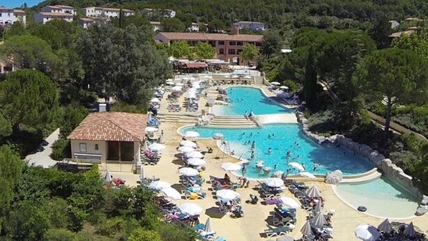 Un complexe hôtelier doté de plusieurs piscines, de chaises longues et offrant une vue sur une colline.
