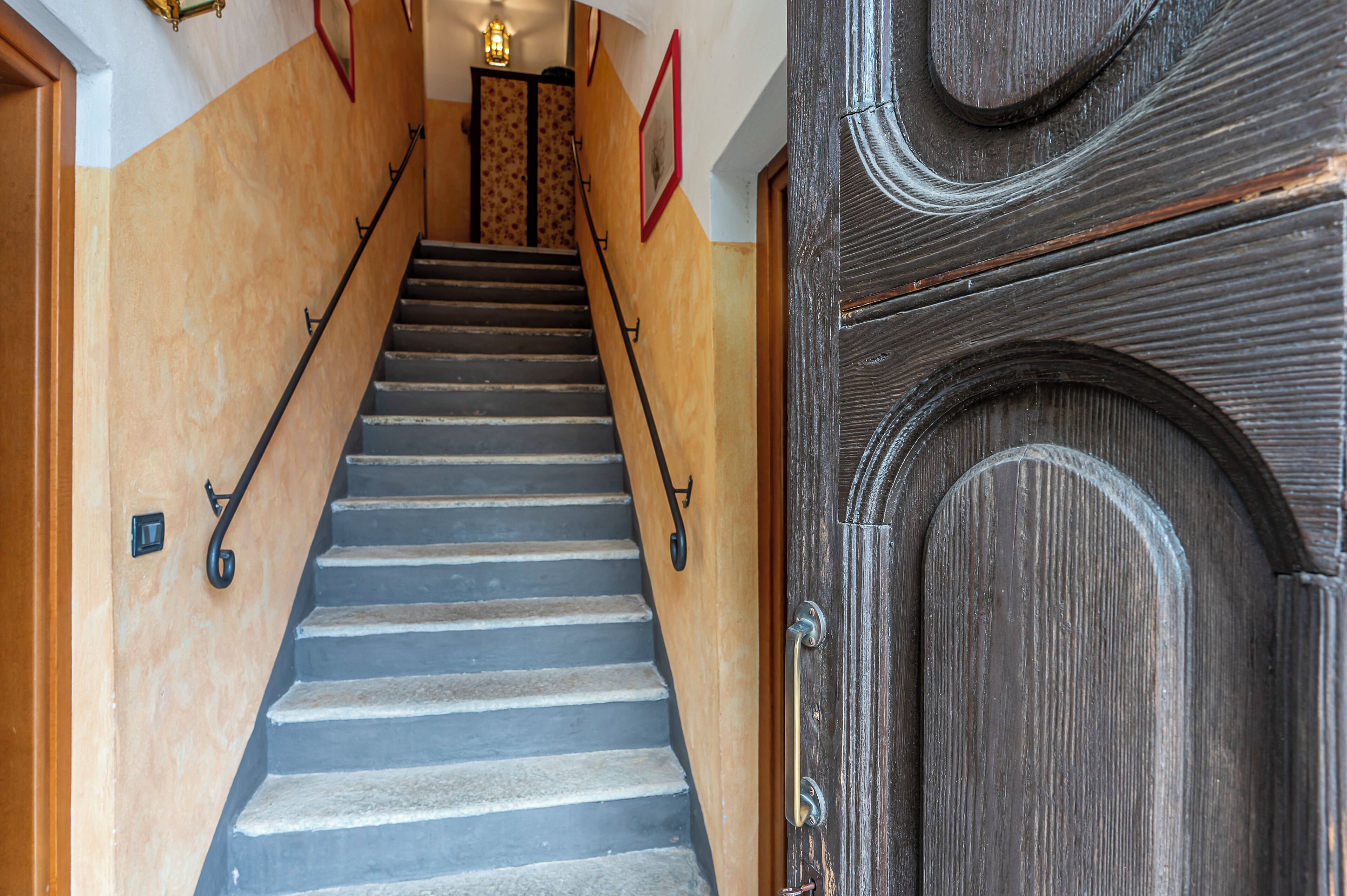 Uma escadaria com corrimão de madeira e uma porta de madeira escura com um design decorativo.