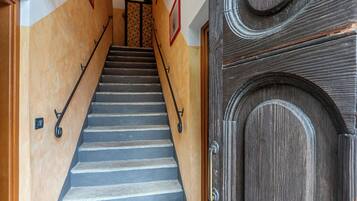 Uma escadaria com corrimão de madeira e uma porta de madeira escura com um design decorativo.