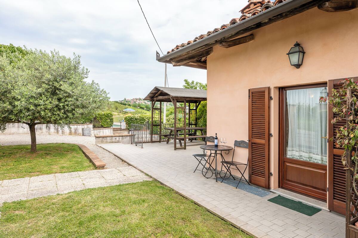 Een huis met een terras, een pergola en een kleine tuin.