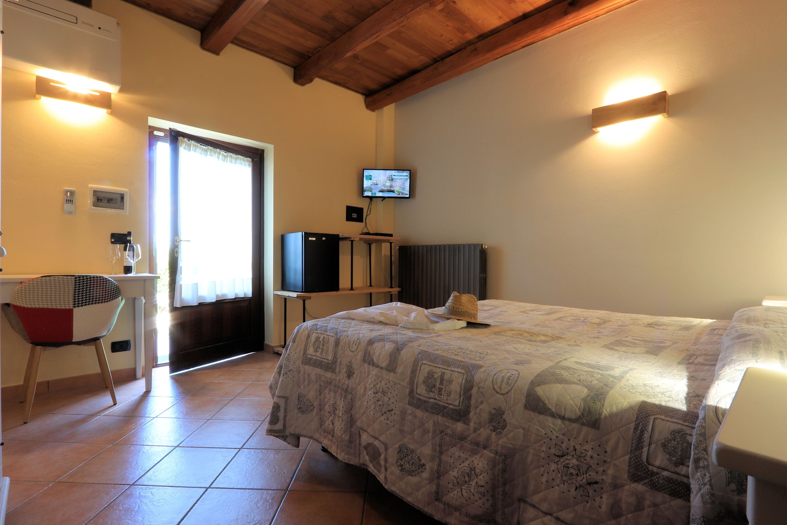 Un dormitorio con cama, escritorio, silla, televisor y ventana.