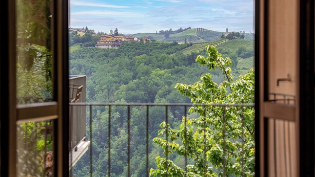 Un balcon offrant une vue sur un paysage verdoyant et luxuriant, avec des collines et un bâtiment visible au loin.