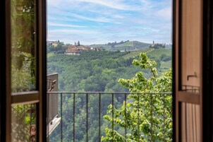 Un balcón con vistas a un paisaje verde exuberante, que incluye colinas y un edificio a lo lejos.