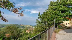 Une vue magnifique depuis un balcon donnant sur une vallée verdoyante, avec un bâtiment visible au loin.