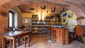 Un coin bar au style rustique, avec des meubles en bois, un plafond en briques et des étagères remplies de bouteilles.