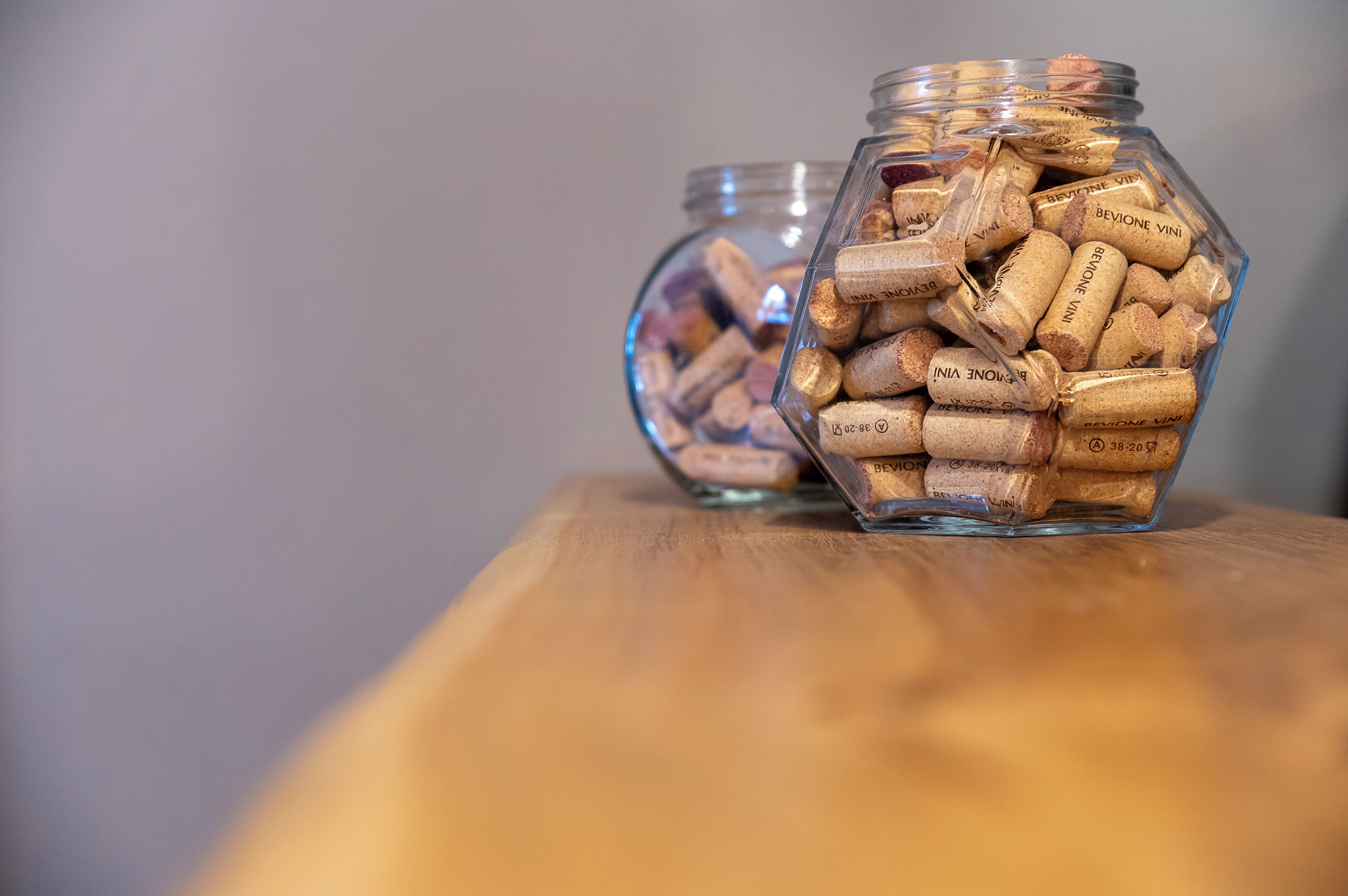 Twee glazen potten gevuld met wijnkurken op een houten ondergrond.