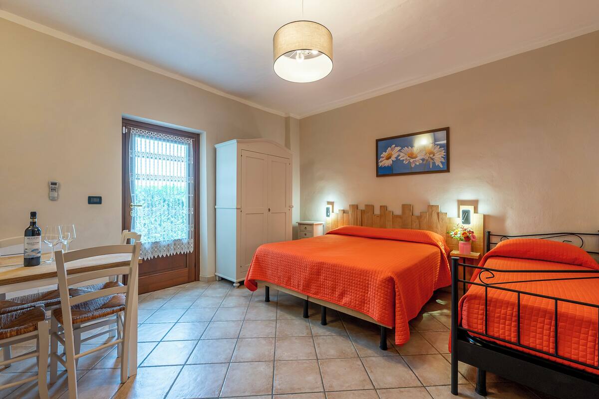 Een slaapkamer met twee bedden, een bureau met stoelen, een kledingkast en een raam met gordijn.