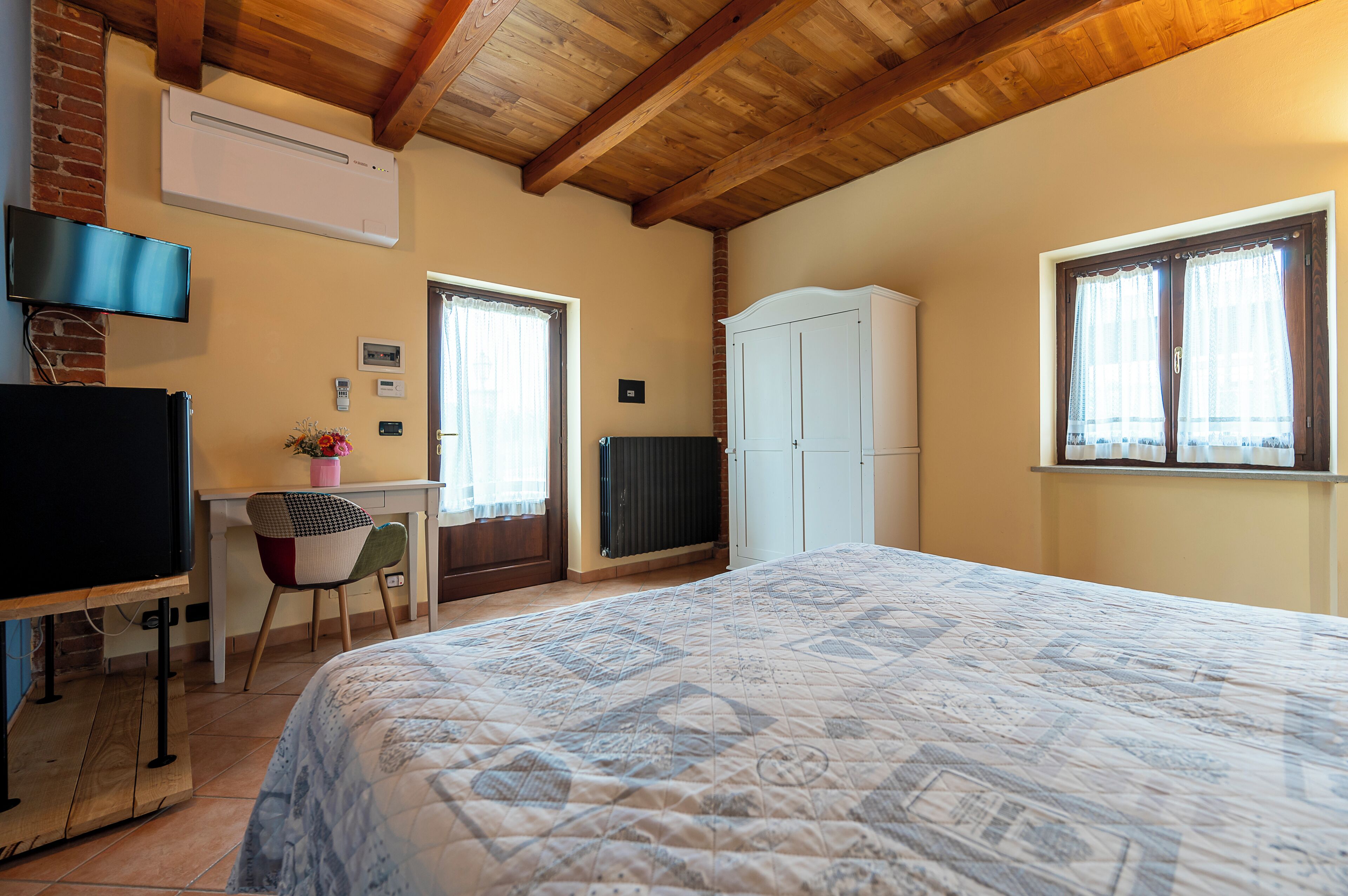 Une chambre à coucher comprenant un lit, un bureau, une chaise, un téléviseur et une armoire.